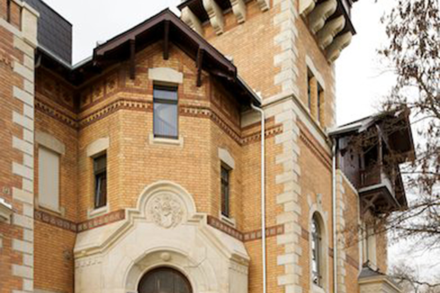 Eingangsseite der Villa mit Rundbogenportal, Freitreppe und h&ouml;lzernem Erker am Turm.