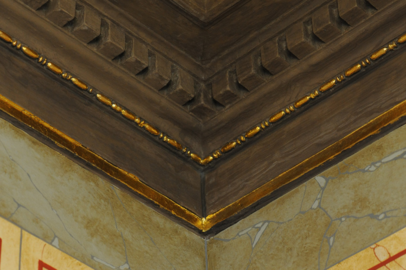 Detail der restaurierten Deckenkehle mit vergoldetem Blattfries &uuml;ber marmorierten Wandfeldern.