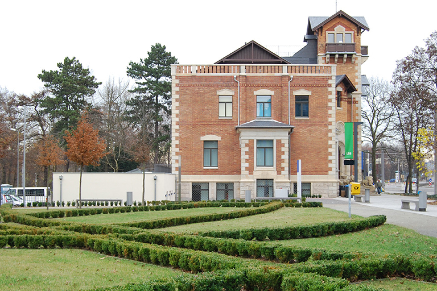 Die Villa hinter der neu angelegten Gartenanlage mit geschnittenen Buchsbaumhecken auf dem Rasen.