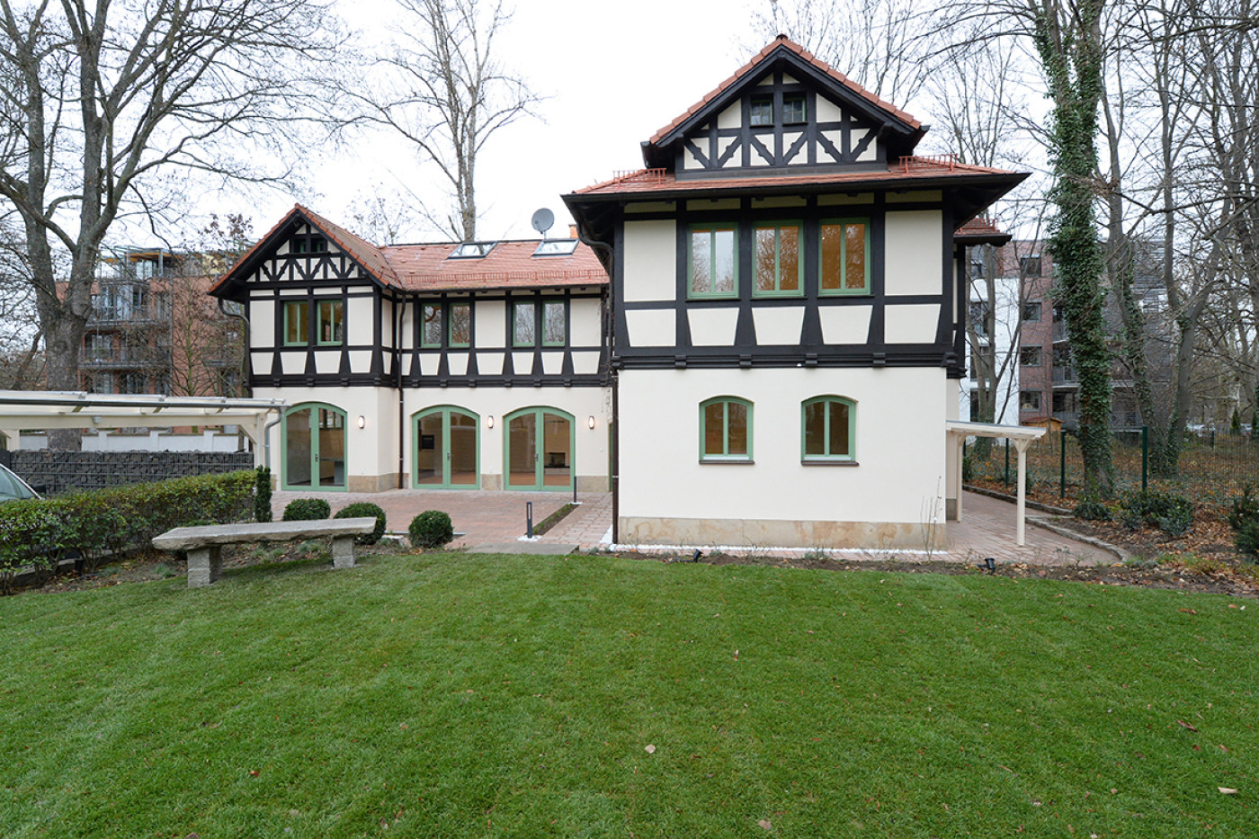 Die sanierte Villa mit Fachwerkgiebeln und rotem Ziegeldach von der Gartenseite, davor eine gro&szlig;e Rasenfl&auml;che.