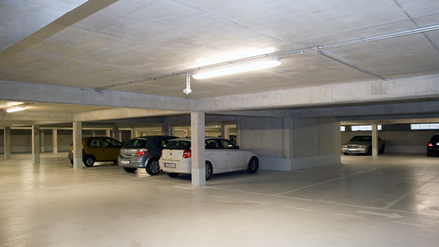 Tiefgarage mit Sichtbetonst&uuml;tzen und Stellpl&auml;tzen unter dem Geb&auml;ude.
