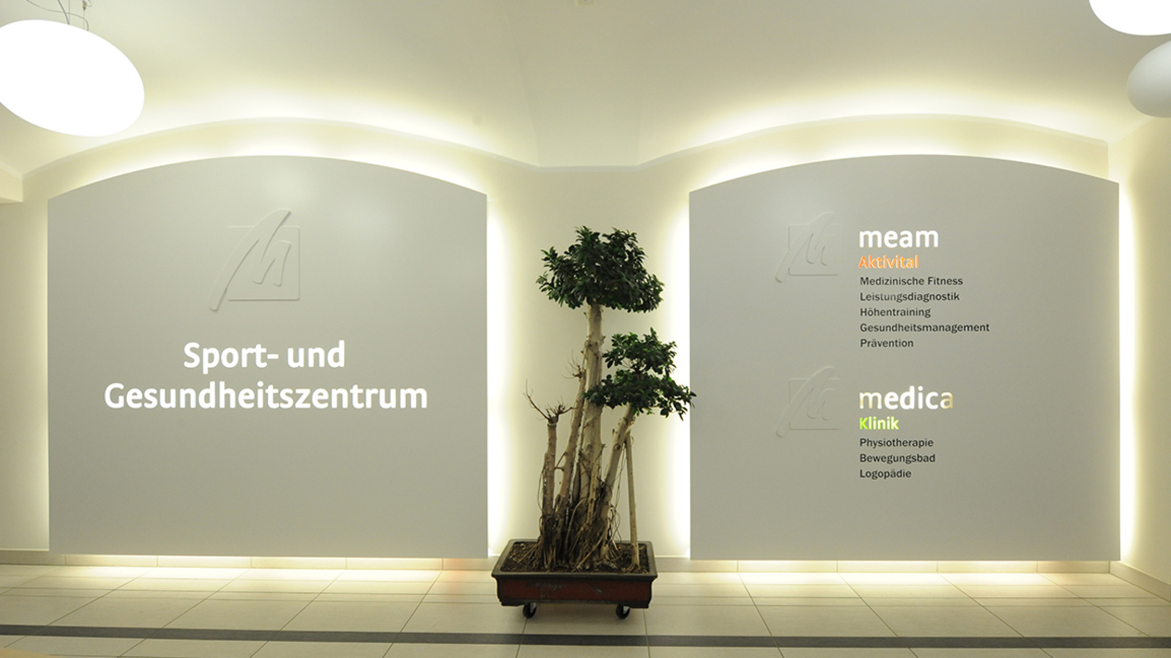 Foyer mit hinterleuchteten Beschriftungsfl&auml;chen in den Wandnischen und einem Formgeh&ouml;lz davor.