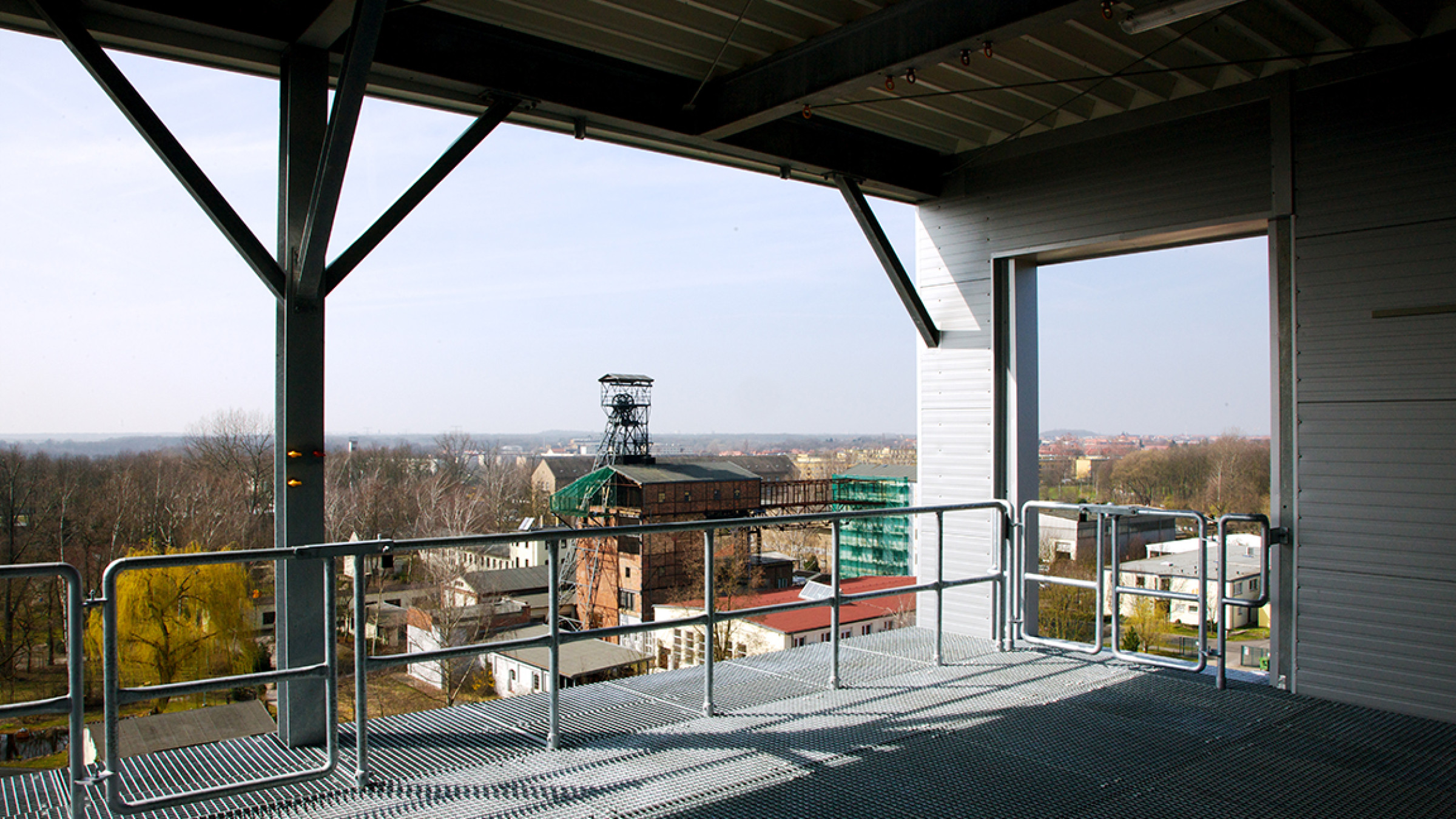 Blick von einer &Uuml;bungsplattform &uuml;ber Gitterrost und Gel&auml;nder auf das Umland mit F&ouml;rderturm.